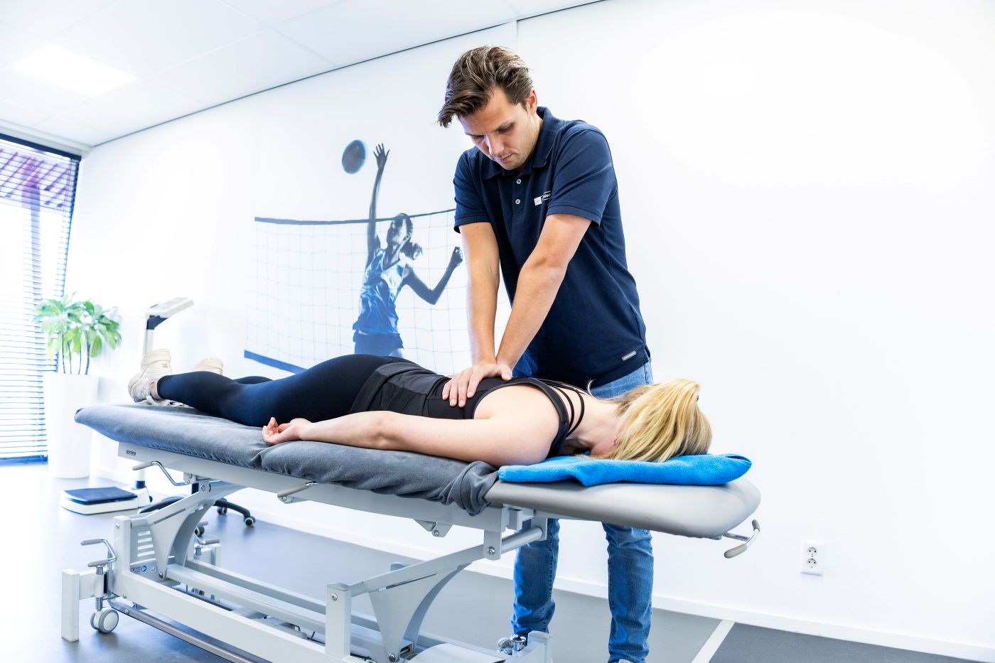 Fysiotherapeut onderzoekt de rug van een patiënt in het Sport & Knie Expertise Centrum Mierlo